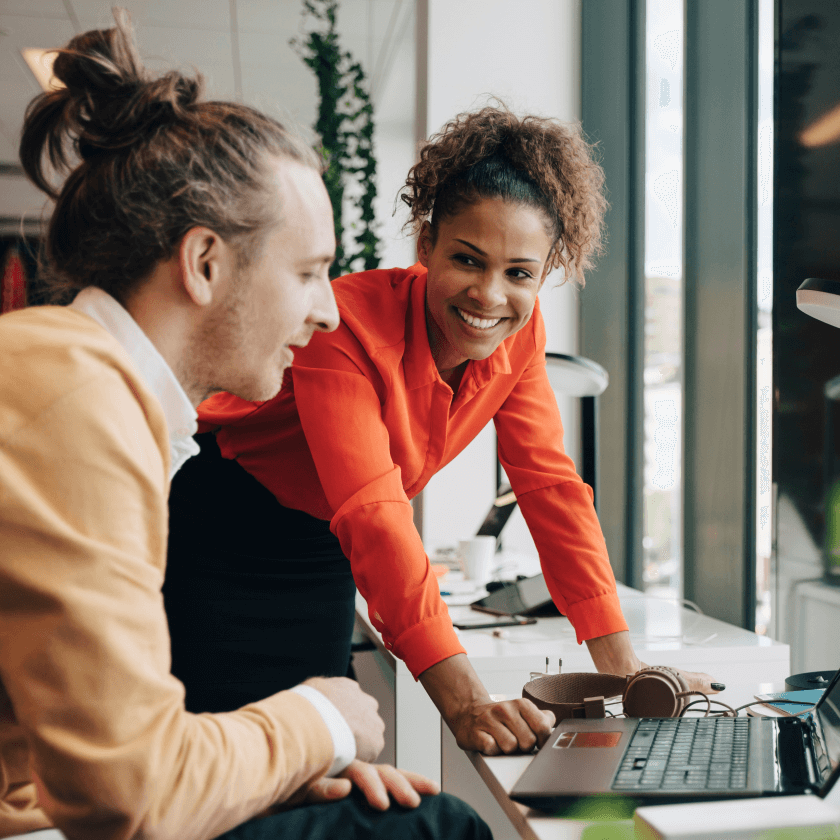 Deux personnes collaborent sur un ordinateur portable, discutant de Docusign dans un bureau lumineux.